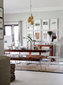 Dark wood table and bench set with metal frames and kitchen chair painted white at head of table in interior with vintage ambiance