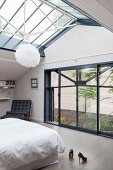 Lichtdurchflutetes Schlafzimmer mit Glasdach und Fensterfront in eleganter Ambiente