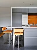 Orange bar stools at counter in grey modern kitchen