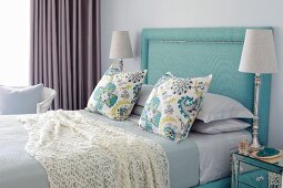 Elegantes Schlafzimmer in Blautönen, Betthaupt mit türkisem Stoff bezogen