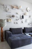 Comfortable, dark grey armchairs below ornaments on small bracket shelves