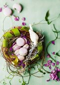 Zartlila Macarons im Nest aus Weidenzweigen mit grünem Schleifenband
