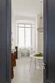 View into dining room with round table, chandelier, and ghost chair