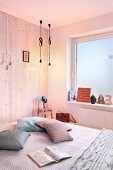 Schlafzimmer mit Holzwand, Fenster mit Milchglasfolie und brennenden Glühbirnen