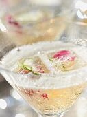 A sparkling wine cocktail with rose petals and lime