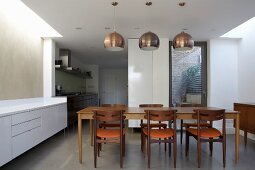 Pendant lamps with metal lampshades above dining set in open-plan kitchen