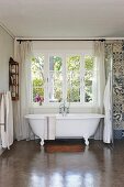 Vintage-style free-standing bathtub below lattice window
