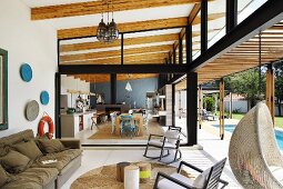 Lounge area with open sliding door in front of open-plan kitchen and dining area