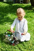 Kleines Mädchen spielt mit Kirschen im Garten