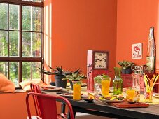Gedeckter Tisch mit Mangodrinks und Vorspeisen in orangefarbenem Raum