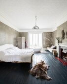 Sleigh bed with slate grey wooden floor in bedroom with free-standing bathtub in background