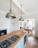 Vintage-Metallpendelleuchten über freistehender Küchenzeile mit blauen, patinierten Landhaus-Fronten und Küchenarbeitsplatte aus Eichenholz