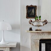 Spring bulbs in antique urn on mantelpiece next to Panthella lamp