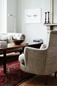 Armchair with ecru upholstery next to coffee table in traditional interior