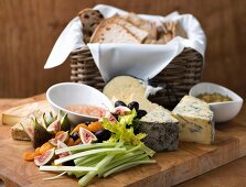 A cheese platter with vegetables, fruit and a bread basket