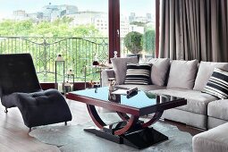 Dark couch and pale grey sofa set around Art Deco coffee table in front of glass wall with a view
