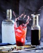 Eiswürfel fällt in Cocktail mit Hibiskussirup und Orangenscheiben