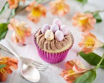 An Easter cupcake with chocolate frosting and mini chocolate eggs