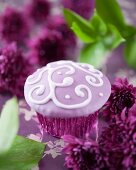 A purple cupcake decorated with a filigree pattern