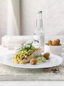 Zander fillet with a herb and potato crust on creamy fennel salad with crispy olives
