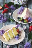 Slices of butter cream cake on plates decorated with flowers and berries