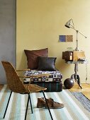 Wicker chair, floor cushions and lamp on retro side table