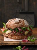 A brown bread burger with mountain cheese, minced lamb, grilled apple and sweet and sour onions