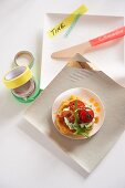 A corn cake with cherry tomatoes, rocket quark and party decorations