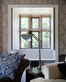 Table lamp on side table between seating in front of lattice window with open interior shutters