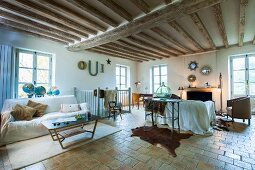 Offener Wohnraum in rustikalem Landhaus mit Holzbalkendecke und Fliesenboden
