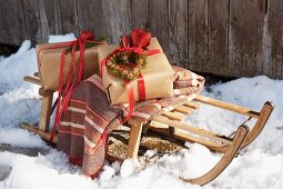 Two gift-wrapped presents and striped blanket on wooden sledge in snow