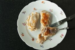 Gebratene Pierogi (Teigtäschchen mit Fleischfüllung, Polen) auf geblümtem Teller