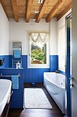 Long, modern bathroom with blue mosaic tiles and wood-beamed ceiling