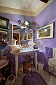 Elegant washstand against lilac walls in crammed bathroom