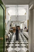 Chequered floor and modern pendant lamps in elegant foyer seen through open door