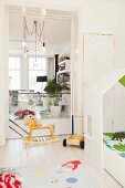 Rocking horse in white, child's bedroom with view into living room