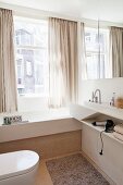 Bright, modern bathroom with custom washstand and fitted bathtub next to window