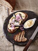 Grilled bread with mayonnaise, sardines in oil and onions
