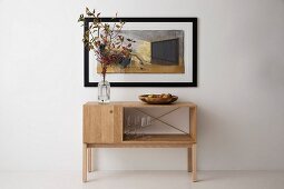 Branches of autumnal leaves on simple, timeless sideboard below picture
