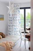 Futon in front of bird-patterned curtain on French doors, paper star and white, bentwood chair