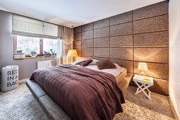 Schlafraum mit Hochflor Teppichboden und stoffbezogener Kassettenrückwand; Doppelbett mit umlaufendem Polsterrand