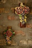 Ceramic crosses decorated with painted ceramic flowers hung on unrendered wall