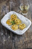 Mini tartlets with apples and rosemary on a porcelain plate and a glass of white wine