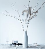Delicate, white paper flowers on dry branches in porcelain vase