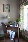 Small wooden desk and Baroque chair next to window with green toile de jouy curtains