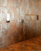 Spacious, floor-level shower with niche shelf and rust-effect tiles
