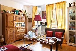 Retro leather sofa, cluttered coffee table and carved wooden cabinet in living room