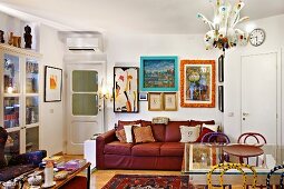 Colourful living room in artist's apartment with comfortable, red leather sofa, various pictures and frames