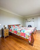 Elegant, antique sleigh bed with patchwork quilt and Oriental bedside cabinet in simple bedroom