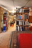 Section of red upholstery on Oriental rug in foreground and bookcase partition in long interior